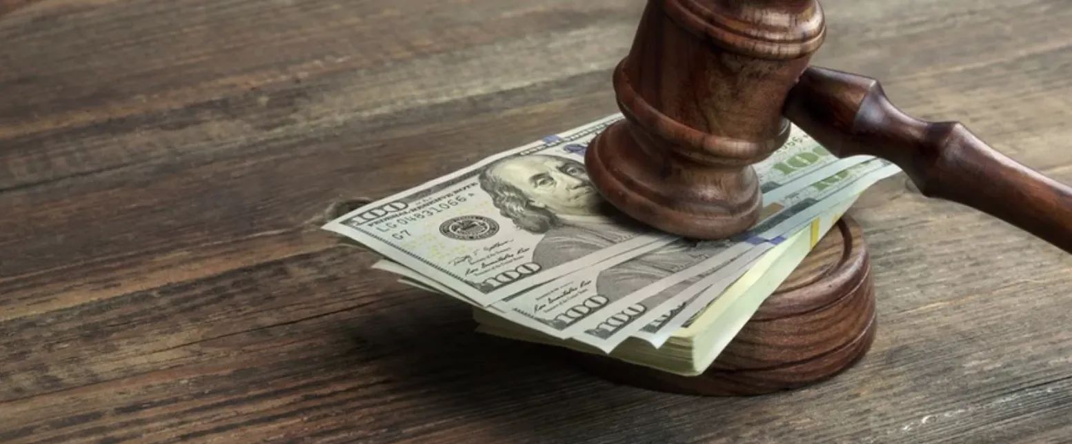 a gavel on top of a stack of 100 dollar bills