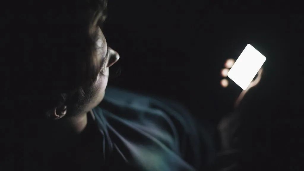 man looking at phone in darkness